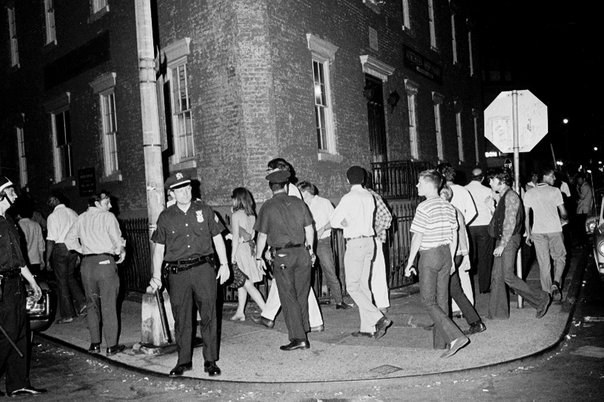 black and white photo of cops looking around sidewalk filled with people